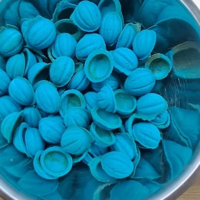 Overhead view of a collection of bright blue plastic bottle caps scattered in a container