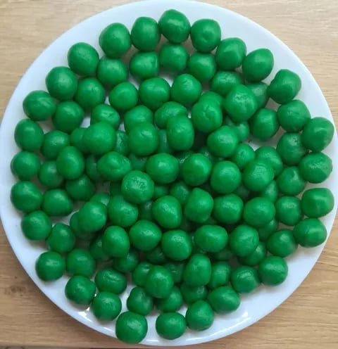 Pile of fresh green limes on a white plate against a wooden surface