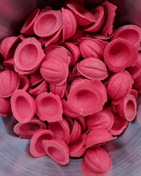 Pink plastic bowl halves scattered in a pile, showing the interior and exterior surfaces of the disposable dishware
