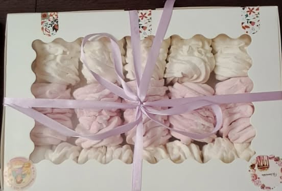 Gift box with decorative meringue cookies in white and pink tied with a purple ribbon bow
