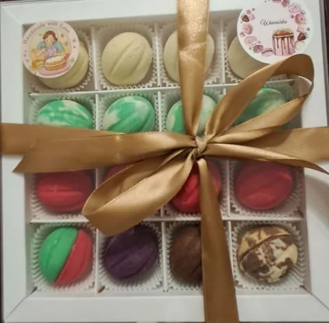 Assorted gourmet chocolates and pastries in white box tied with gold ribbon bow