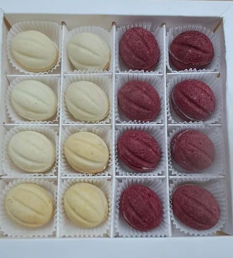 Box of assorted truffles with eight white cream truffles on the left and eight burgundy wine truffles on the right, each in individual paper cups