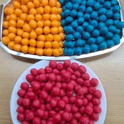 Two white bowls filled with colorful round candies: orange and blue spheres on top, pink spheres below