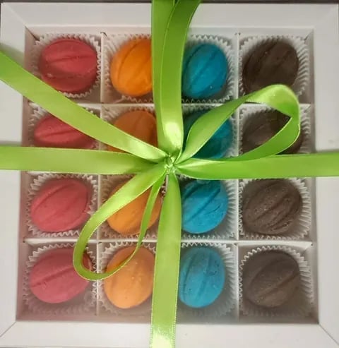 Assorted colorful macarons in a gift box tied with a bright green ribbon bow