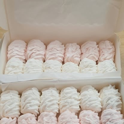 Box of assorted meringue cookies in white and pale pink arranged in rows
