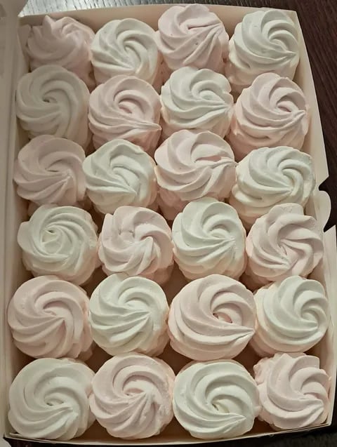 Box of 24 piped meringue cookies in white and pale pink, arranged in rows in cardboard packaging