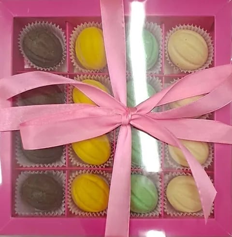 Pink gift box containing 16 colorful assorted chocolates wrapped with a pink ribbon bow