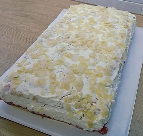 Rectangular sheet cake on white plate with cream frosting topped with diced pineapple pieces