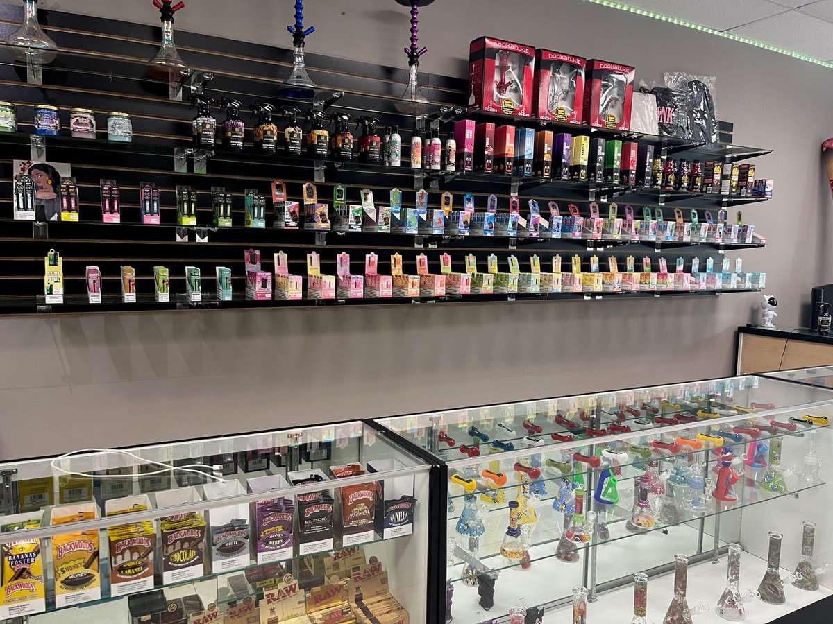 Beauty supply store with nail polish bottles displayed on black wall shelves and products in glass display cases below