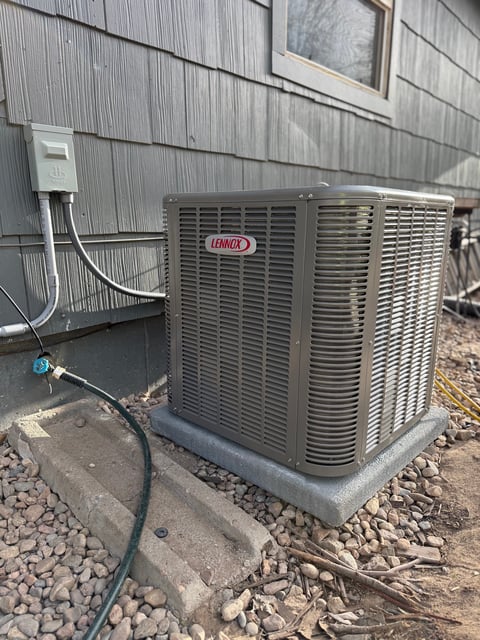Lennox air conditioning unit mounted on concrete pad outside metal-sided building
