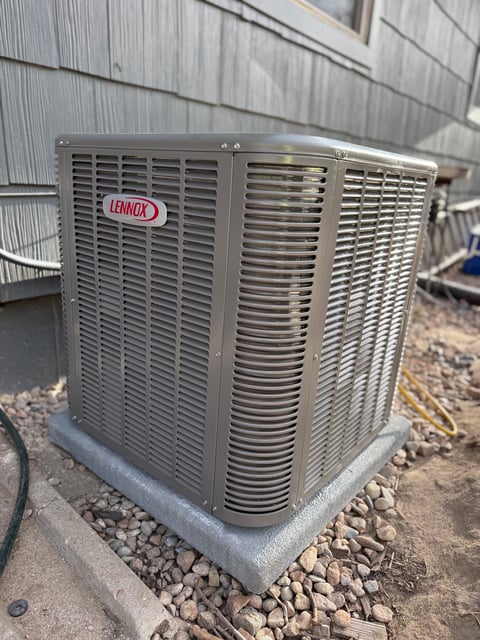 Lennox air conditioning unit outdoor condenser mounted on concrete pad with gravel surrounding it