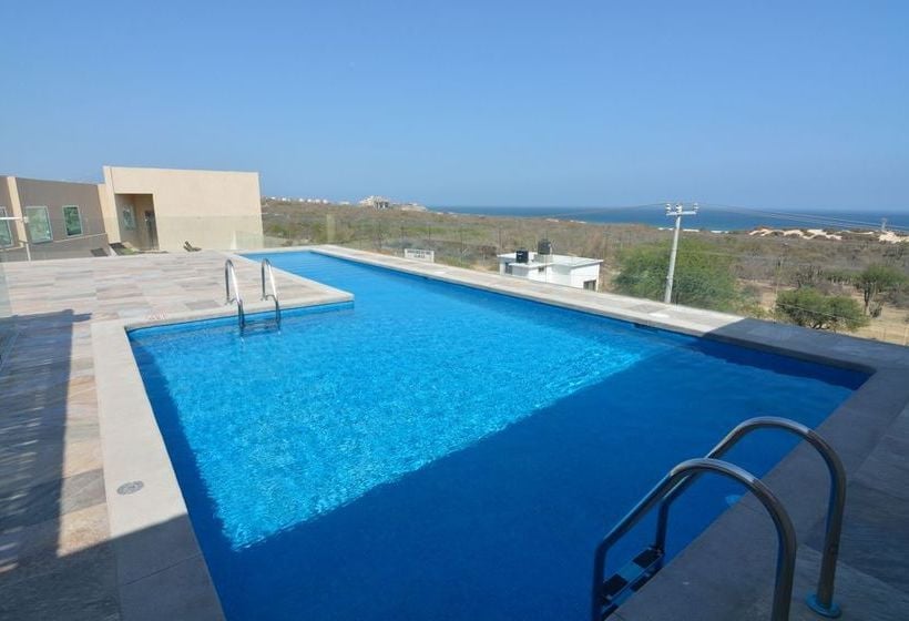 Alberca con agua azul brillante en terraza con vista al mar, escalera de acceso y arquitectura moderna blanca