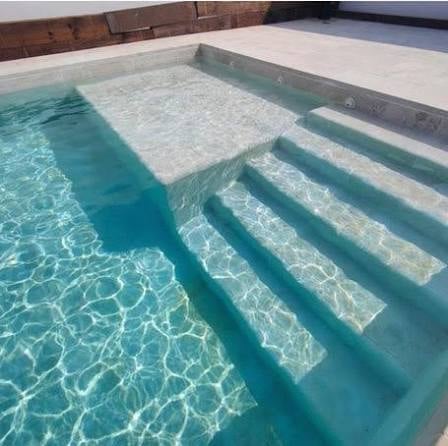 Alberca moderna con agua turquesa, escalones de concreto y área de spa en construcción