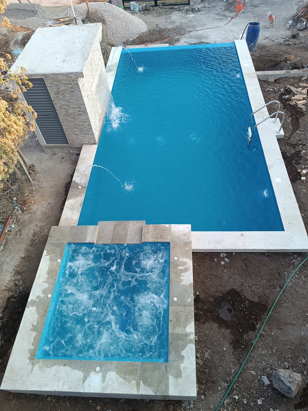 Vista aérea de alberca residencial en construcción con deck de concreto y equipo alrededor de la piscina con forro azul