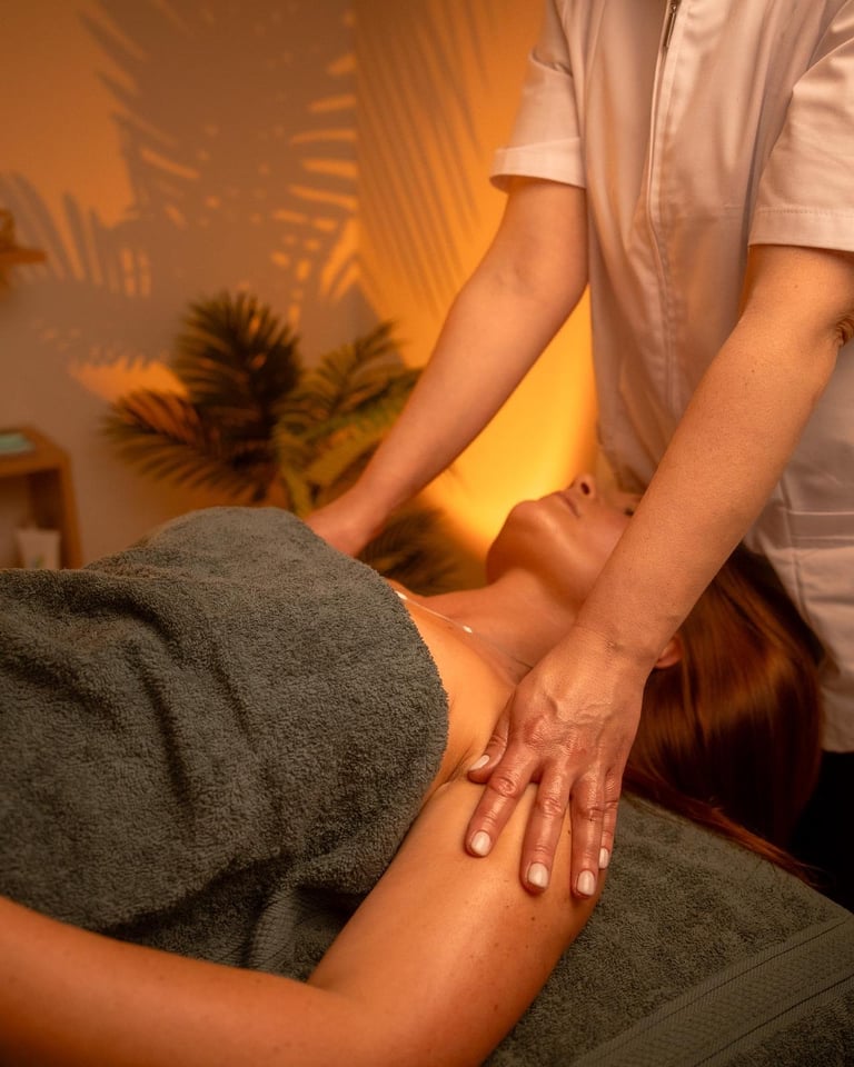 Massagista a realizar massagem terapêutica em ambiente de spa com iluminação quente e plantas