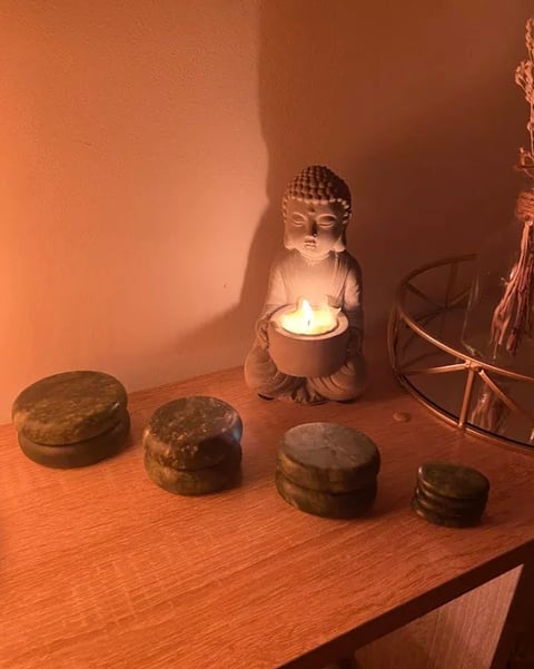 Figuras de Buda com vela e pedras empilhadas em luz âmbar