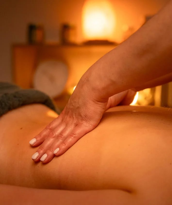 Terapeuta a realizar massagem nas costas em ambiente de spa iluminado a velas