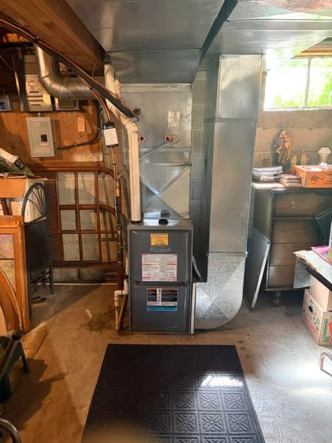 Interior of a mobile home showing entrance area with wooden door, furnace unit, kitchen appliances, and storage items along the walls