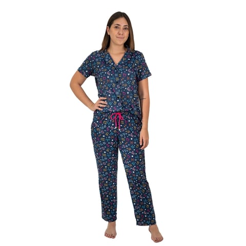 Woman wearing dark blue floral pajama set with short sleeves and pink drawstring waist, standing barefoot against white background