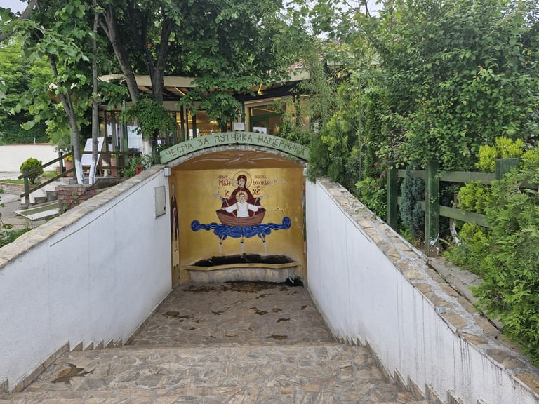 Underpass with religious mural featuring figure in lotus position, white walls on sides, surrounded by green trees and vegetation