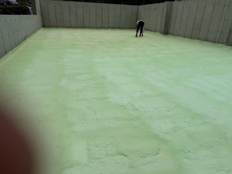 Person standing in a large concrete pit or enclosed area with pale green floor surface and metal walls