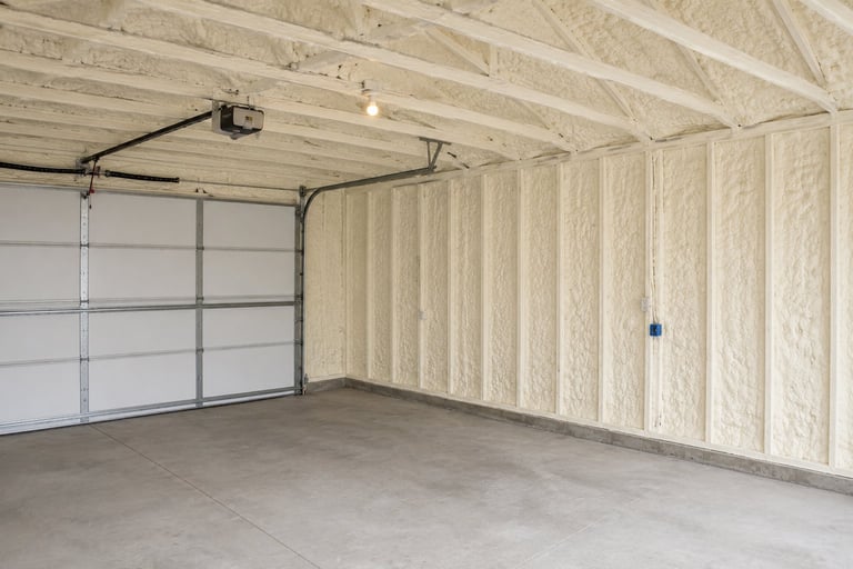 Empty garage interior with white panel door, concrete floor, and exposed wooden ceiling beams