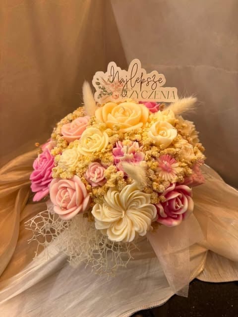 Floral bridal bouquet with pink, yellow, and cream roses, babys breath, and wooden topper, wrapped with tulle ribbon.