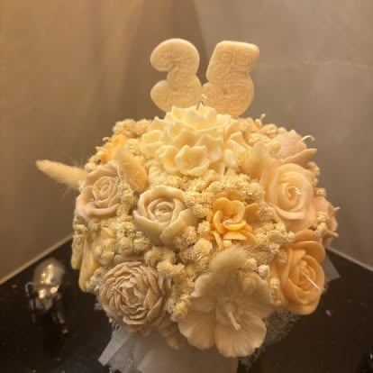Elegant tiered wedding cake decorated with cream and peach fondant roses, topped with number 25 cake toppers