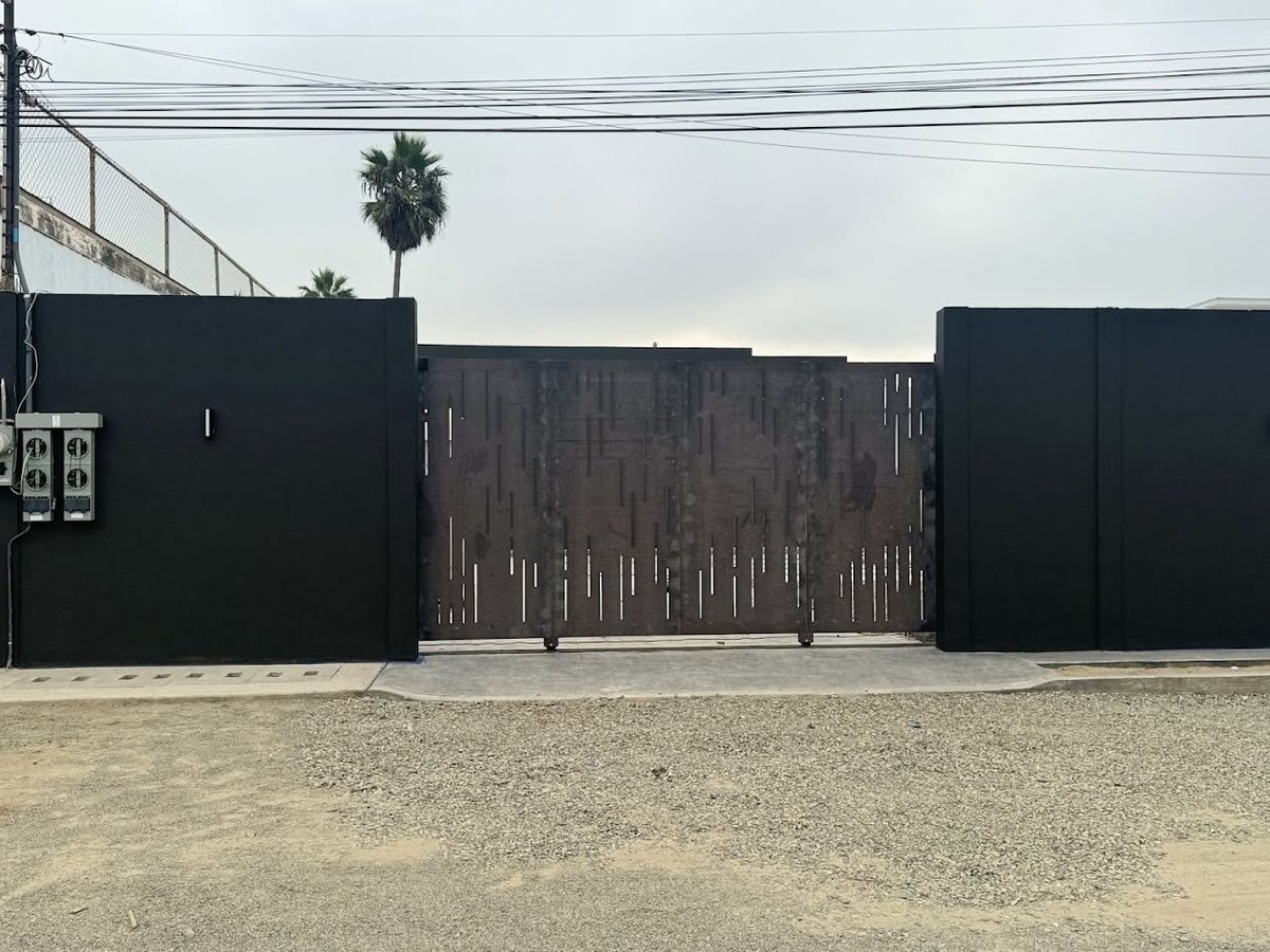 Portones metálicos y reja de herrería de precisión en entrada residencial — corte CNC de acero