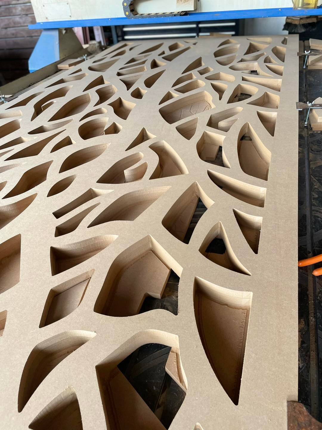 Panel MDF con cortes curvos orgánicos en router CNC para diseño de mobiliario contemporáneo