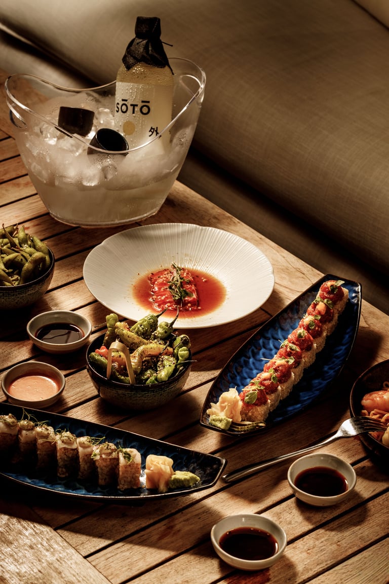 Elegant plated sushi and Japanese appetizers with ice bucket cocktail on wooden table