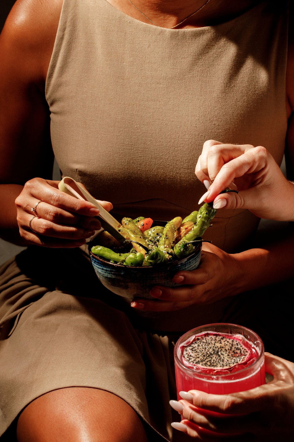 Person in beige shirt holding bowl of green salad and jar of seeds, healthy eating concept