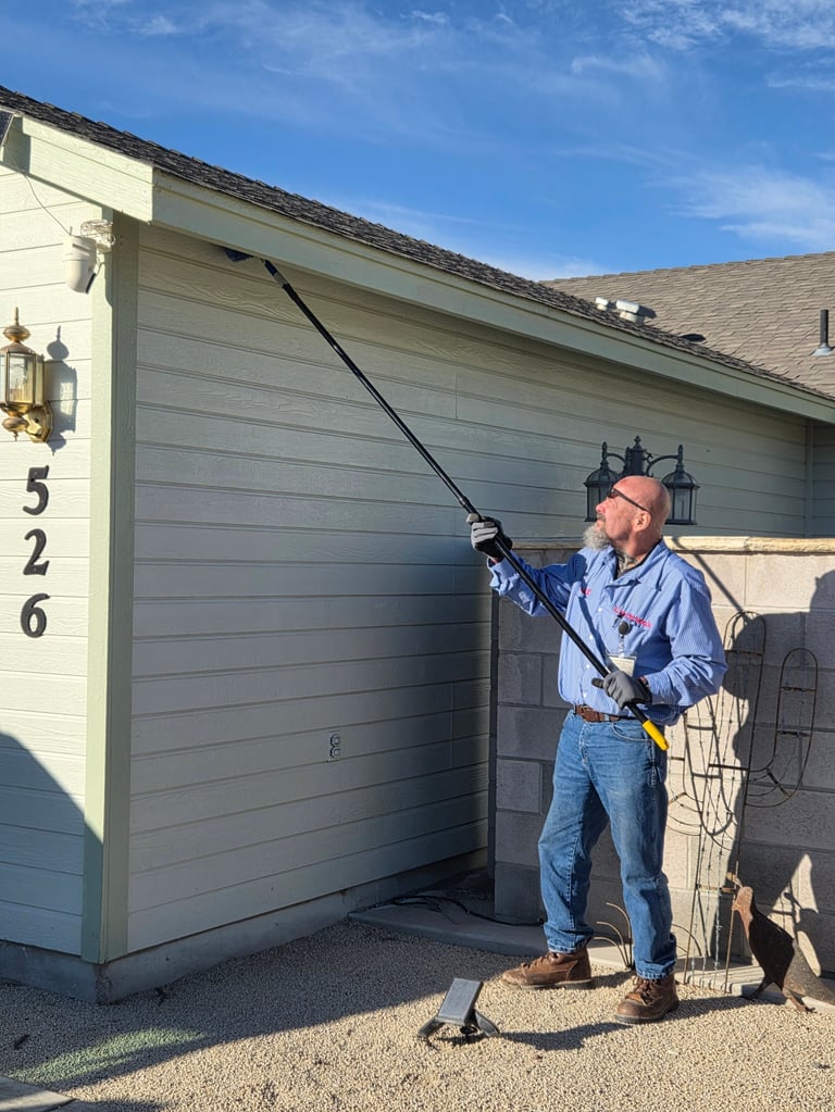 Man in blue shirt and hat using a pole to open a gray garage door, with house number 526 visible