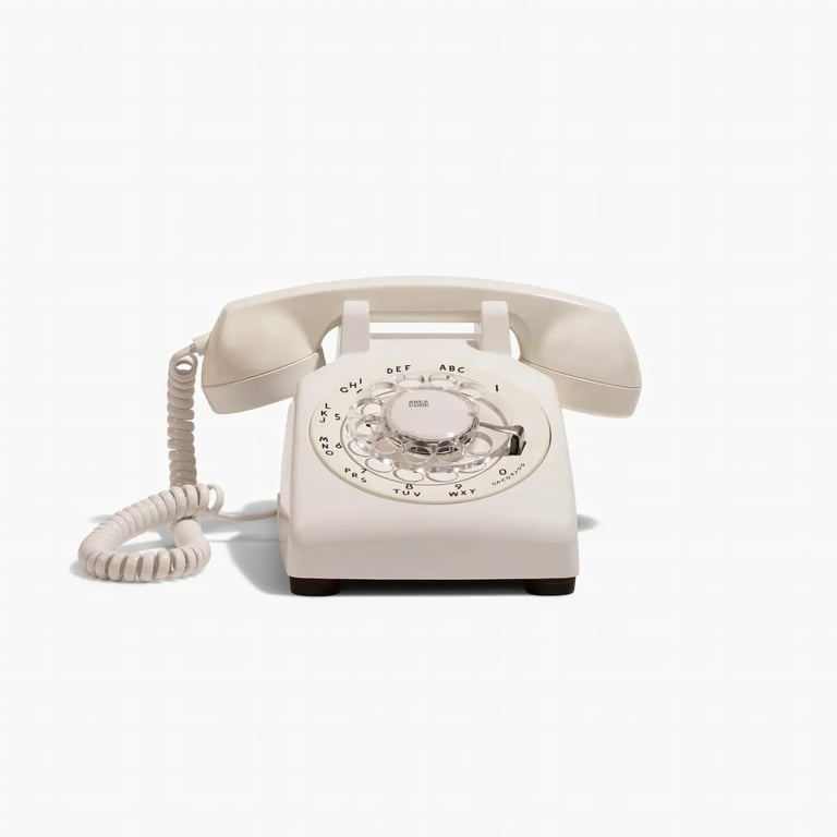 Vintage cream-colored rotary telephone with coiled cord and handset on white background
