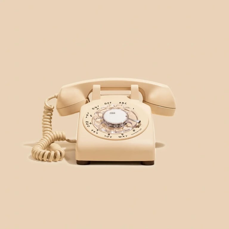 Vintage cream-colored rotary telephone with curled handset cord on beige background