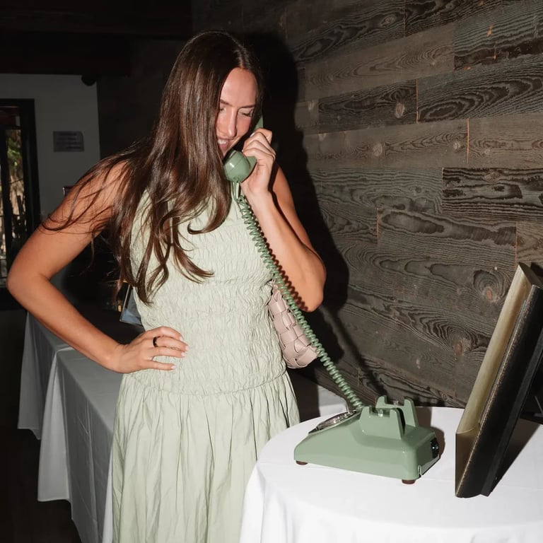 Woman in light green dress talking on vintage rotary phone at indoor event