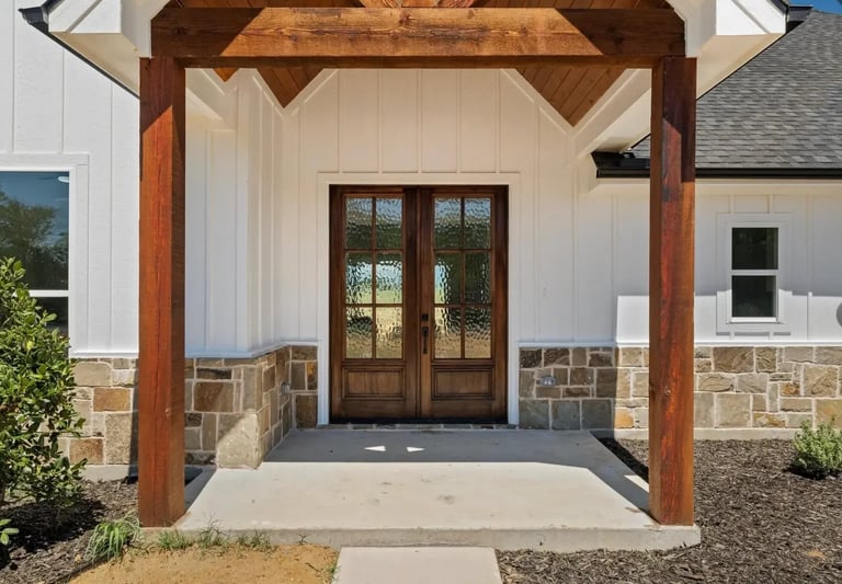 Modern farmhouse entry with wooden pergola and dark wood double doors — Southern Shore custom details