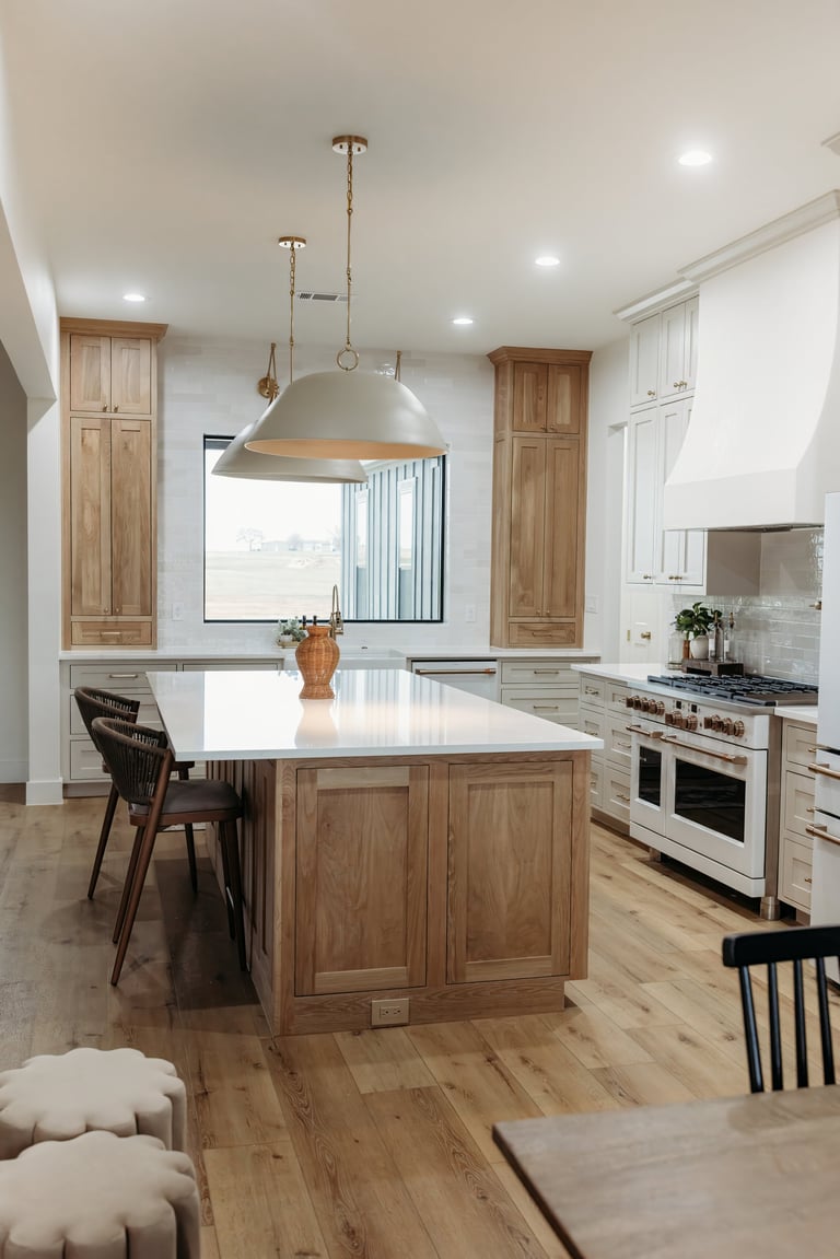 Kitchen in the completed Whitesboro custom home — large natural-wood island, stainless steel appliances, pendant lighting and a mix of wood and white cabinetry