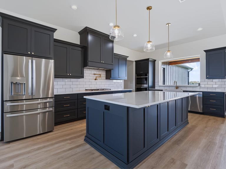 Modern kitchen with dark blue cabinets, white quartz countertops, stainless steel appliances, and pendant lighting over central island