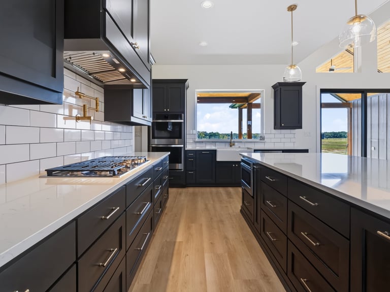 Modern kitchen with black cabinets, white subway tile backsplash, gas cooktop, and wood flooring overlooking a scenic landscape view