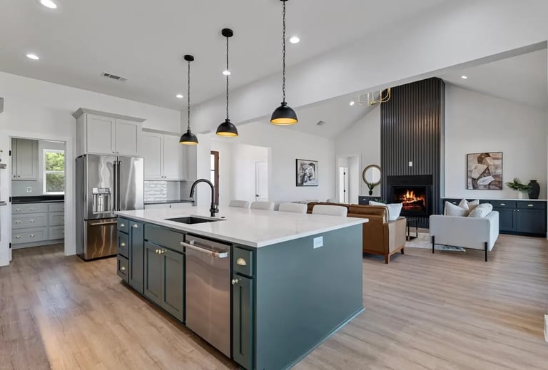 Modern open-concept kitchen with teal island, stainless steel appliances, pendant lights, and living room with fireplace