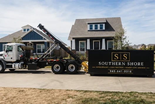 Southern Shore construction truck and dumpster in front of two residential homes under renovation on a driveway
