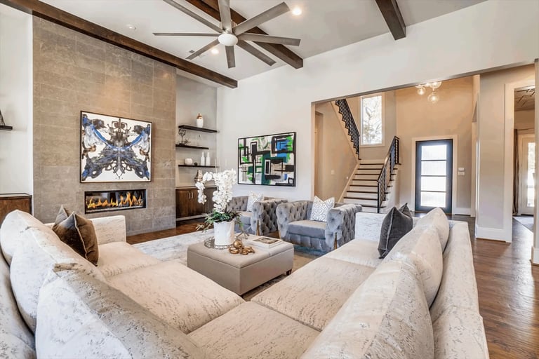 Modern living room with cream sectional sofa, fireplace, coffee table, and exposed ceiling beams with skylights