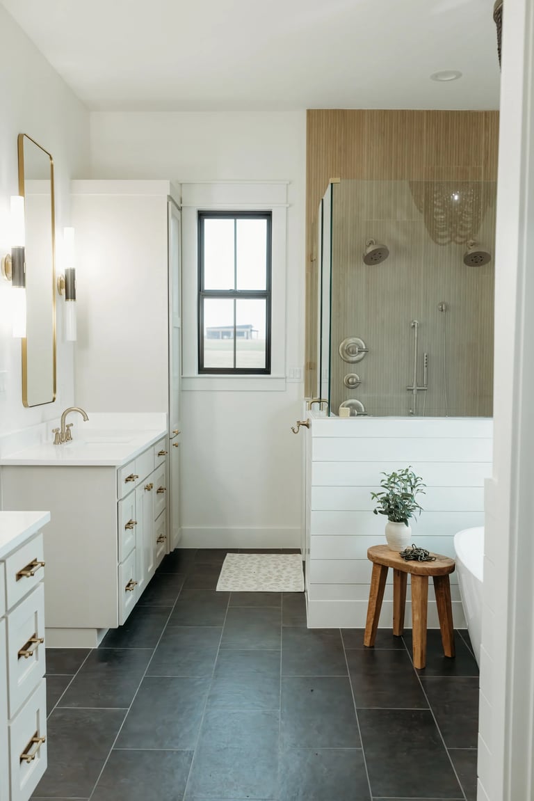 Modern bathroom with white vanities, dark tile flooring, glass walk-in shower with wood accent wall
