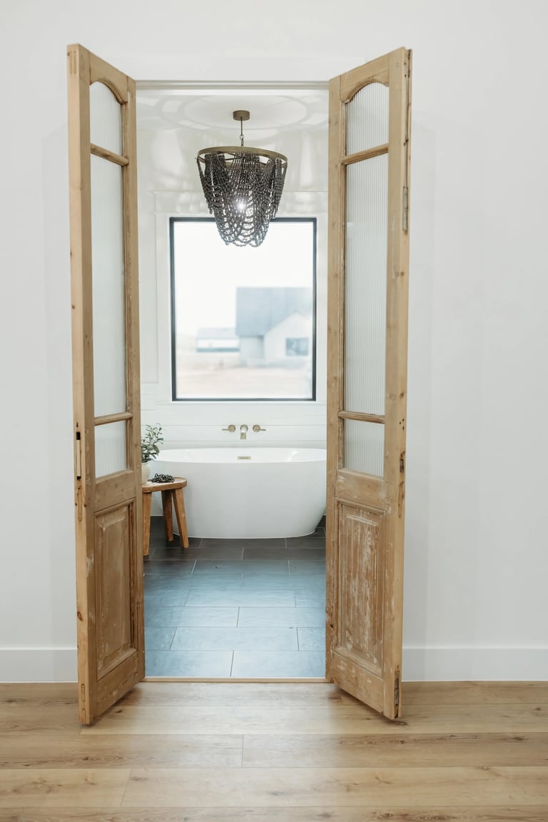 Bright bathroom with freestanding tub, pendant light, and large window