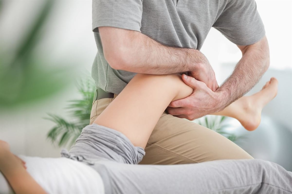 Physiotherapist performing manual leg massage or physical examination on patients calf muscle