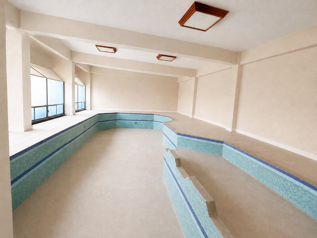 Empty room with cream walls, blue-tiled wainscoting, white ceiling, recessed lights, and windows along one wall
