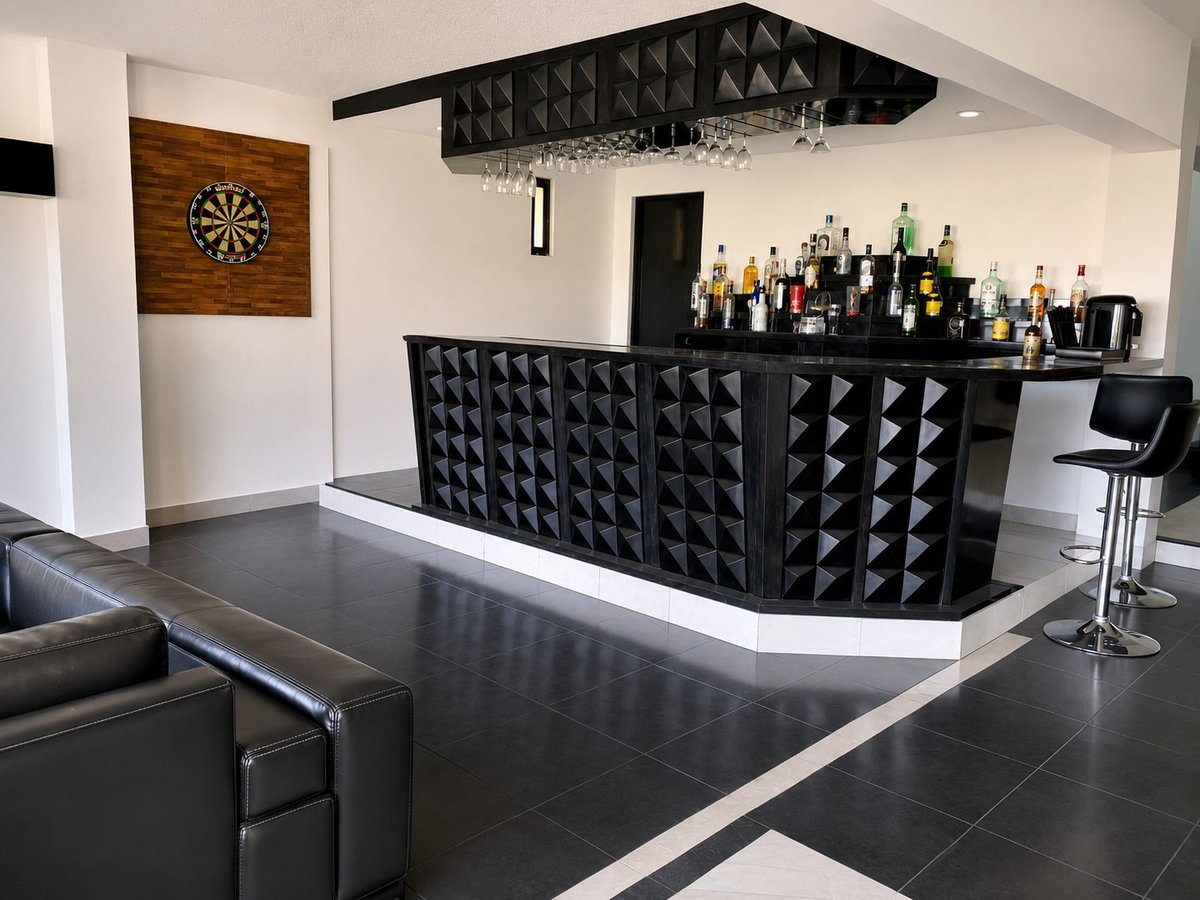 Modern home bar with black geometric 3D paneled counter, white top, and shelves of liquor bottles against white walls