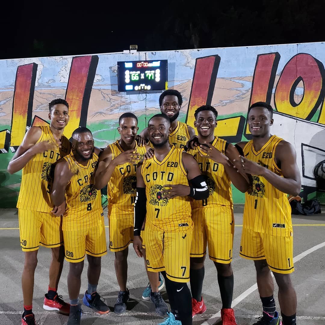 Seven male basketball players in yellow COTO uniforms posing together