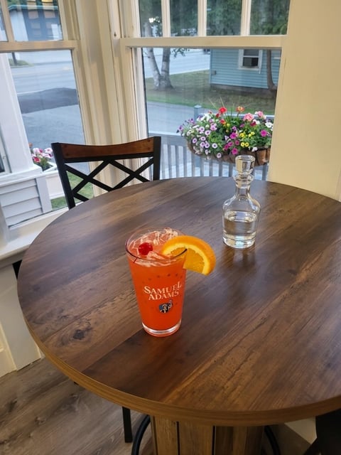 A Samuel Adams beer and glass of water on a wooden table
